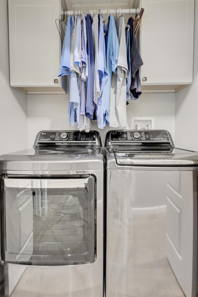 clothes washing area with cabinets and washing machine and dryer