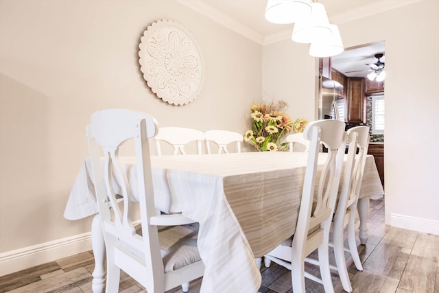 dining room with ornamental molding, a ceiling fan, baseboards, and wood tiled floor