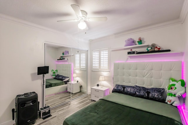 bedroom featuring ceiling fan, a closet, light wood-style flooring, and crown molding