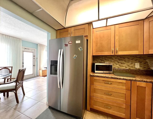 kitchen featuring decorative backsplash, light tile patterned flooring, stainless steel appliances, and a textured ceiling