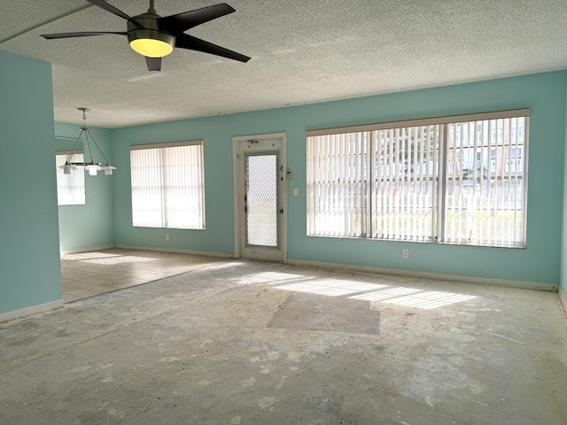 unfurnished living room featuring ceiling fan, plenty of natural light, and a textured ceiling