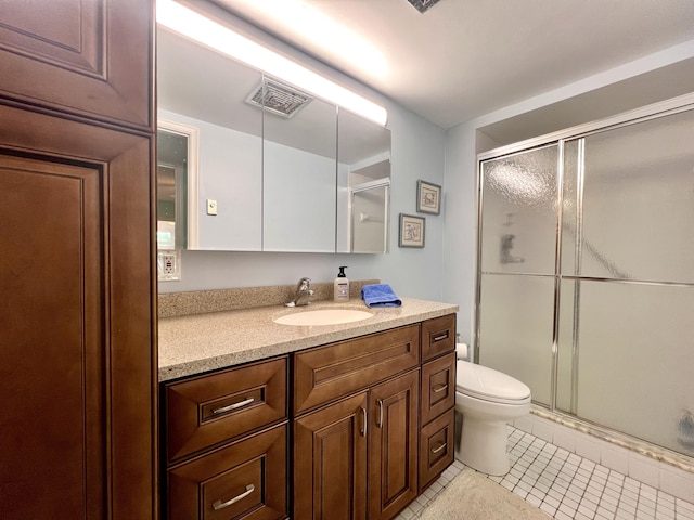 bathroom featuring tile patterned floors, a shower with door, vanity, and toilet