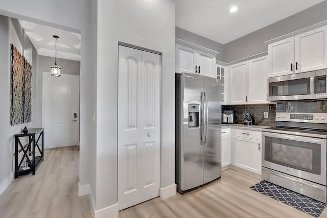 kitchen with light wood-type flooring, appliances with stainless steel finishes, decorative backsplash, and white cabinetry