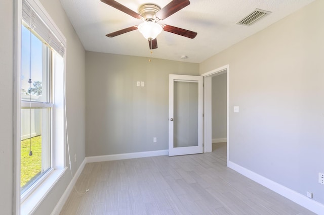 unfurnished room featuring ceiling fan, light hardwood / wood-style floors, a wealth of natural light, and french doors