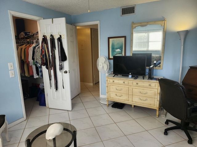 tiled bedroom with a walk in closet, a textured ceiling, and a closet