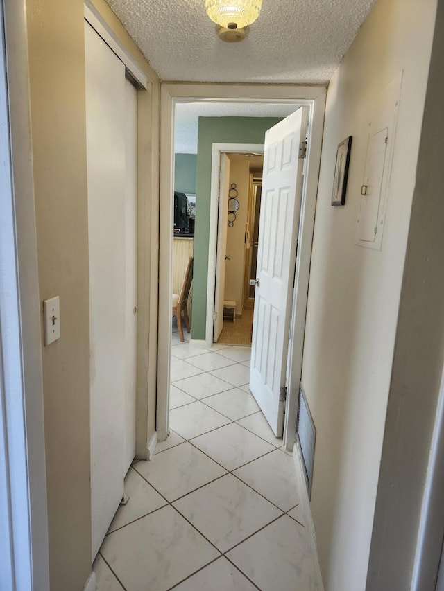 corridor with light tile patterned floors and a textured ceiling