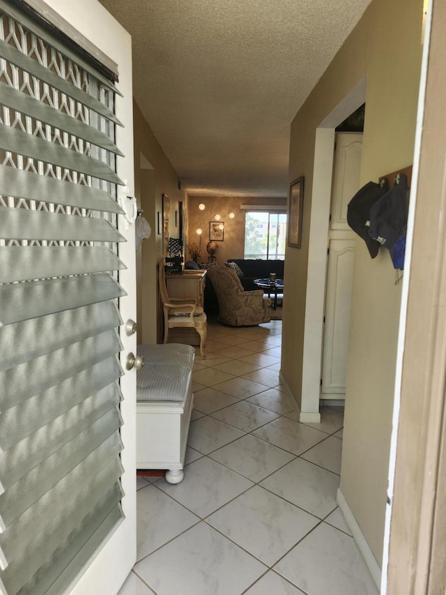 hallway featuring light tile patterned floors and a textured ceiling