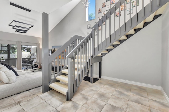 stairs featuring high vaulted ceiling and an inviting chandelier