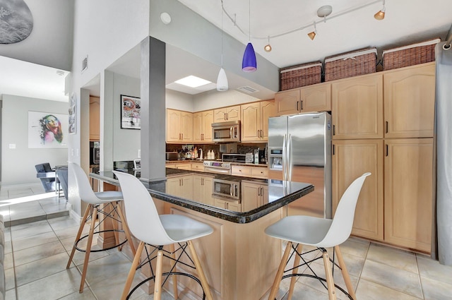 kitchen featuring a kitchen breakfast bar, light tile patterned floors, stainless steel appliances, and light brown cabinetry