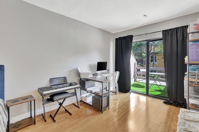 home office with light hardwood / wood-style floors and a textured ceiling