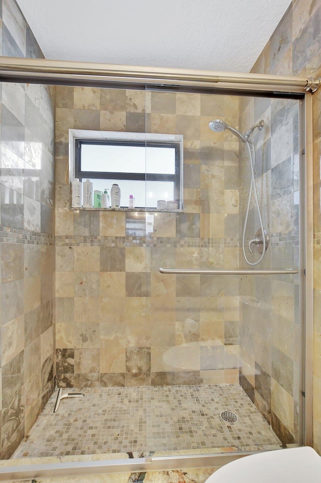 bathroom with a shower with door and toilet