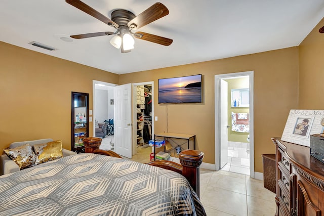 tiled bedroom featuring ceiling fan, a closet, a spacious closet, and ensuite bath