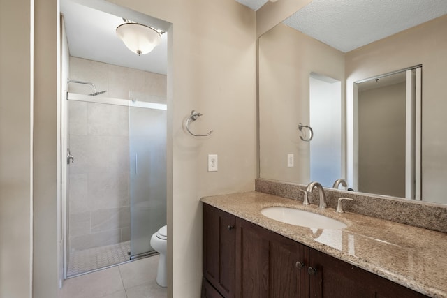 bathroom featuring vanity, a shower with door, tile patterned floors, toilet, and a textured ceiling