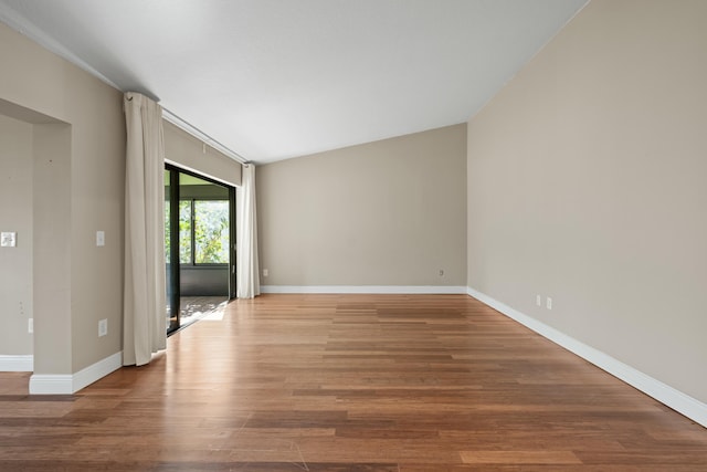 empty room featuring lofted ceiling and wood-type flooring