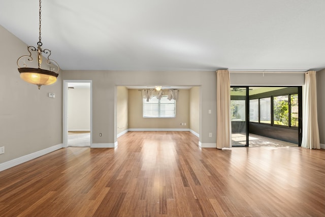 unfurnished living room featuring hardwood / wood-style flooring and an inviting chandelier