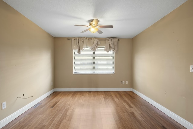 empty room with ceiling fan, a textured ceiling, and light wood-type flooring