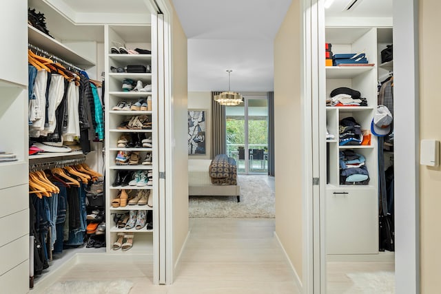 walk in closet with an inviting chandelier and light hardwood / wood-style flooring