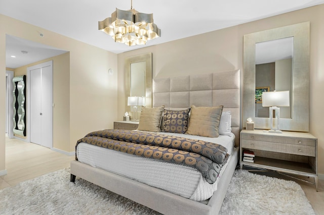 bedroom with wood finished floors, baseboards, and an inviting chandelier
