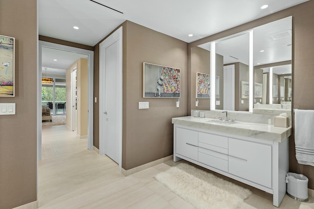 bathroom with baseboards, vanity, and recessed lighting