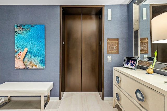 interior space with baseboards, elevator, and light wood-style flooring