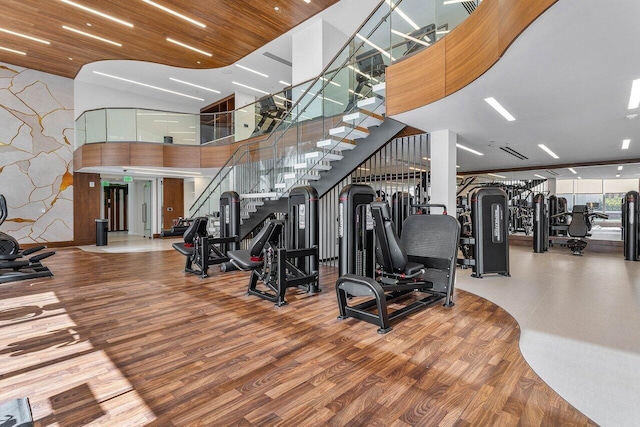 exercise room with wood finished floors and a high ceiling