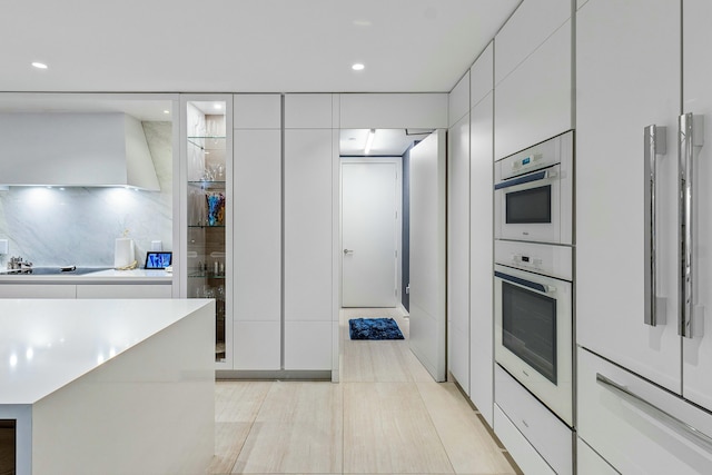 kitchen with backsplash, white cabinets, black electric cooktop, and wall chimney exhaust hood