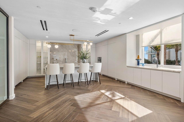 kitchen featuring hanging light fixtures, a breakfast bar area, modern cabinets, light countertops, and white cabinets