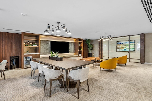 interior space featuring wine cooler, wood walls, an inviting chandelier, and light colored carpet