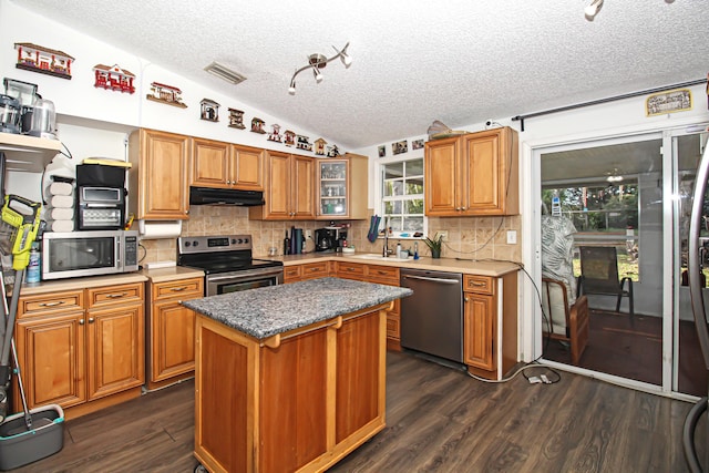 kitchen featuring dark hardwood / wood-style floors, a center island, lofted ceiling, and appliances with stainless steel finishes