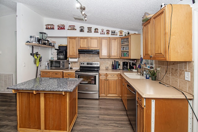 kitchen featuring sink, dark hardwood / wood-style floors, vaulted ceiling, a kitchen island, and appliances with stainless steel finishes