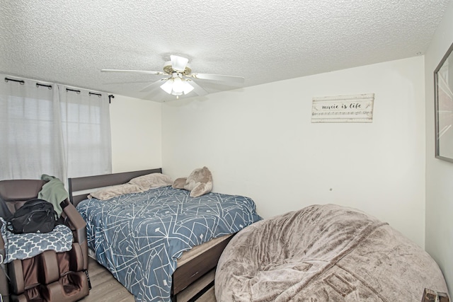 bedroom featuring ceiling fan, light wood-type flooring, and a textured ceiling