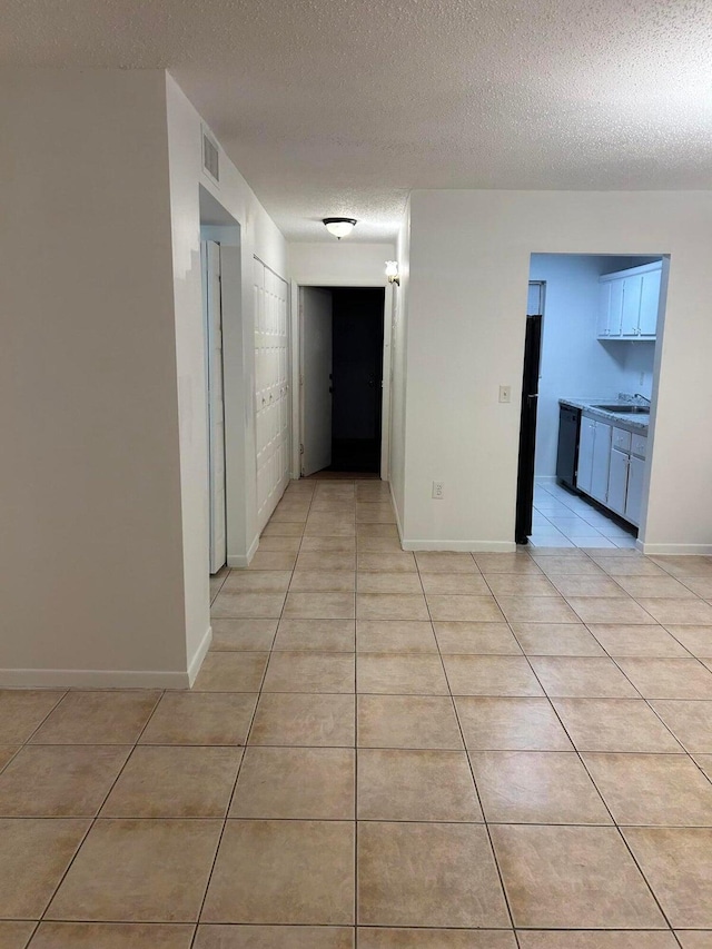 corridor with sink, light tile patterned floors, and a textured ceiling