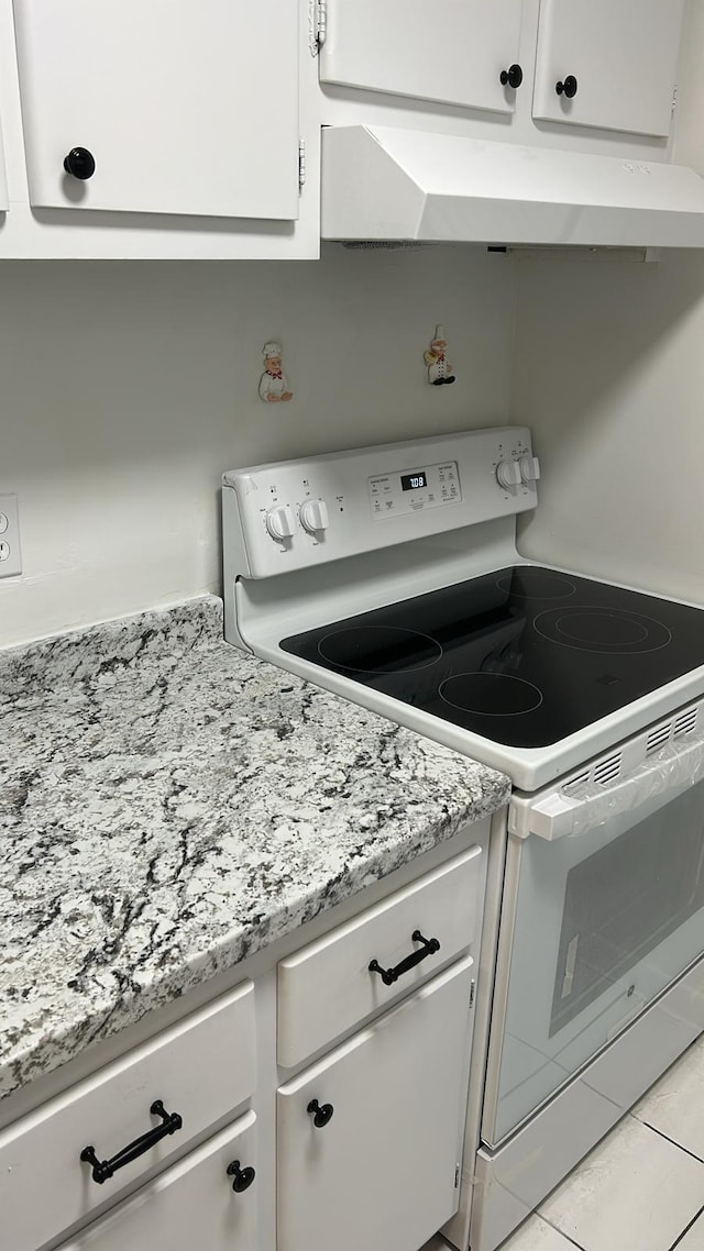 kitchen featuring white cabinets, light tile patterned flooring, and electric stove