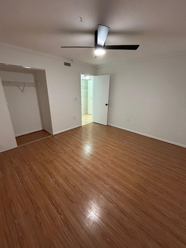 unfurnished bedroom featuring a closet, ceiling fan, dark hardwood / wood-style flooring, and ornamental molding