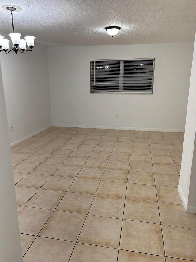 unfurnished room with a chandelier, light tile patterned floors, and a textured ceiling