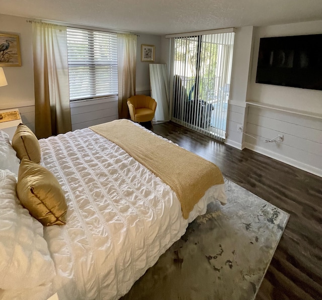 bedroom with a textured ceiling, dark hardwood / wood-style flooring, and access to outside