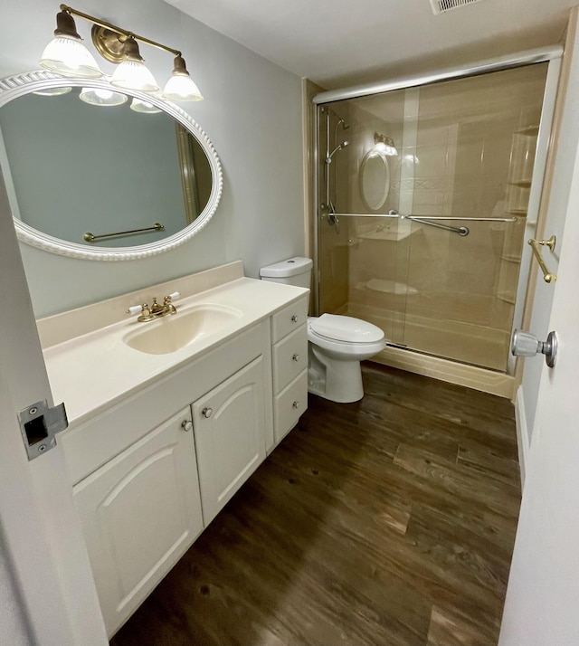 bathroom featuring a shower with door, vanity, wood-type flooring, and toilet