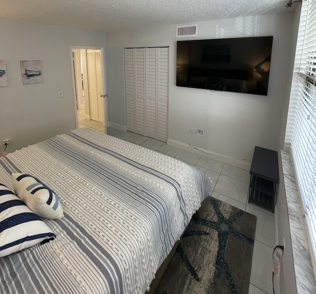 bedroom featuring a closet, light tile patterned flooring, and a textured ceiling