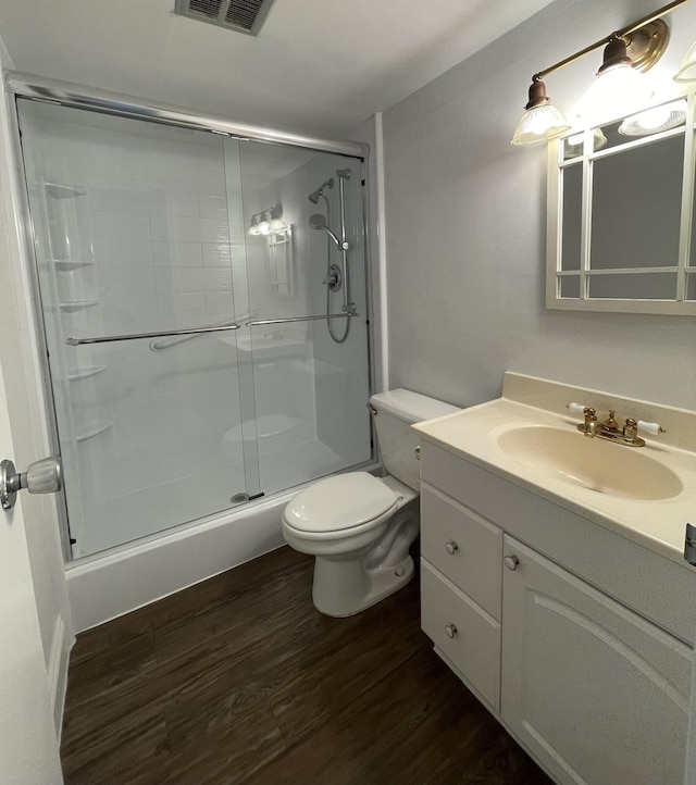 bathroom featuring hardwood / wood-style floors, vanity, a shower with shower door, and toilet