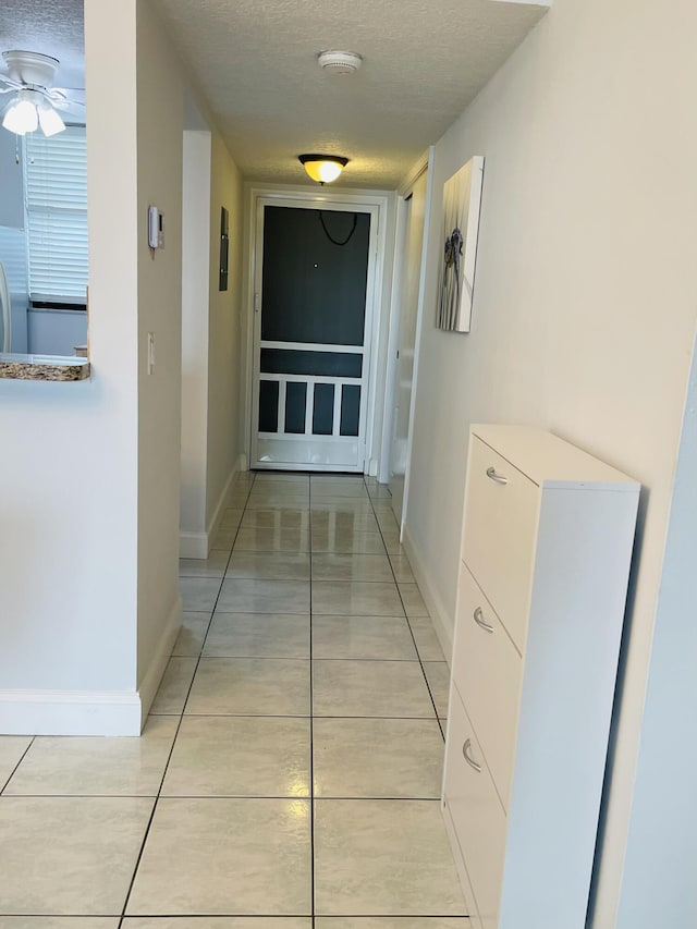 corridor featuring a textured ceiling and light tile patterned flooring