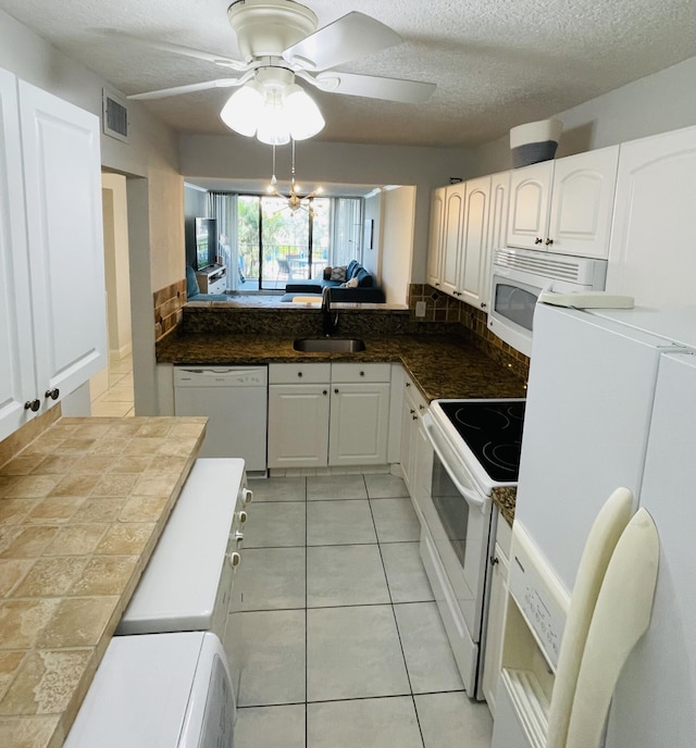 kitchen featuring a textured ceiling, white appliances, sink, light tile patterned floors, and white cabinets