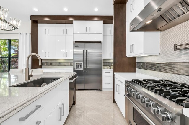 kitchen with decorative backsplash, gas range, white cabinets, and wall chimney range hood