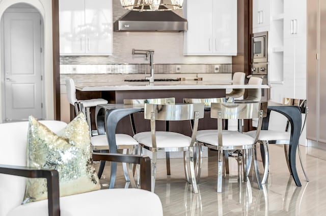 bar with white cabinets, dark brown cabinetry, backsplash, and light stone countertops