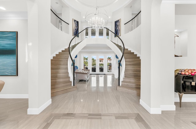 foyer entrance with french doors, a chandelier, a high ceiling, and ornamental molding