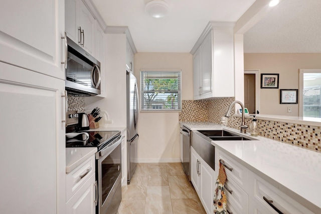 kitchen with white cabinets, sink, appliances with stainless steel finishes, and tasteful backsplash