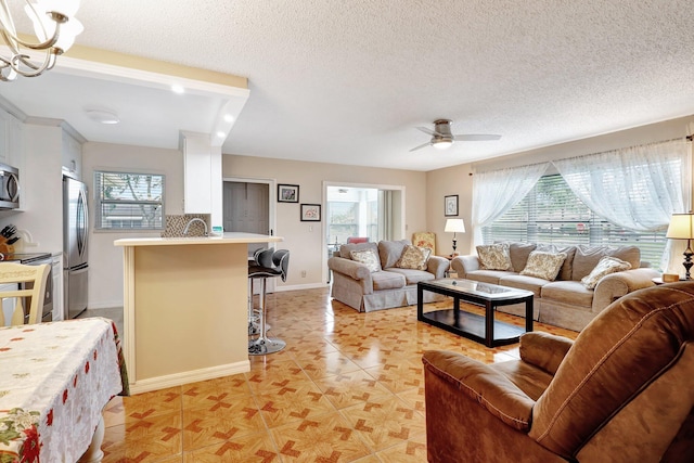 living room featuring ceiling fan, a healthy amount of sunlight, and a textured ceiling