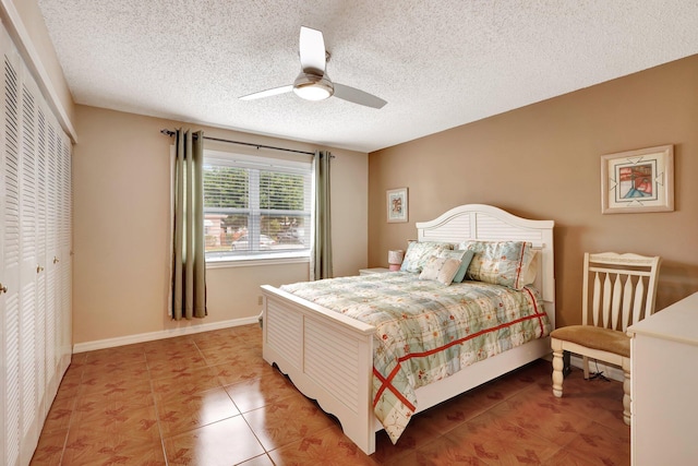 bedroom with tile patterned floors, ceiling fan, a textured ceiling, and a closet