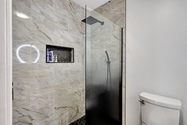 bathroom with a tile shower and toilet