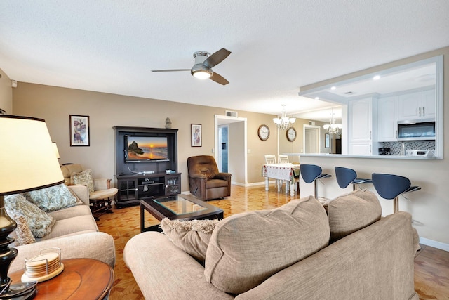 living room featuring a textured ceiling, ceiling fan with notable chandelier, and light parquet flooring