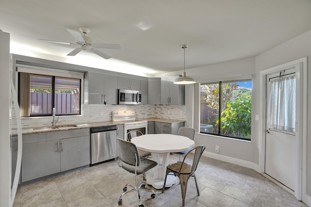 kitchen with decorative light fixtures, decorative backsplash, gray cabinets, appliances with stainless steel finishes, and sink